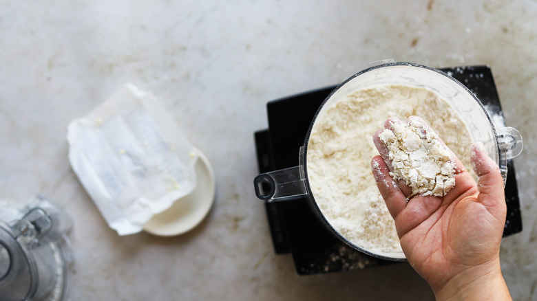 hand mixing flour mixture in food processor