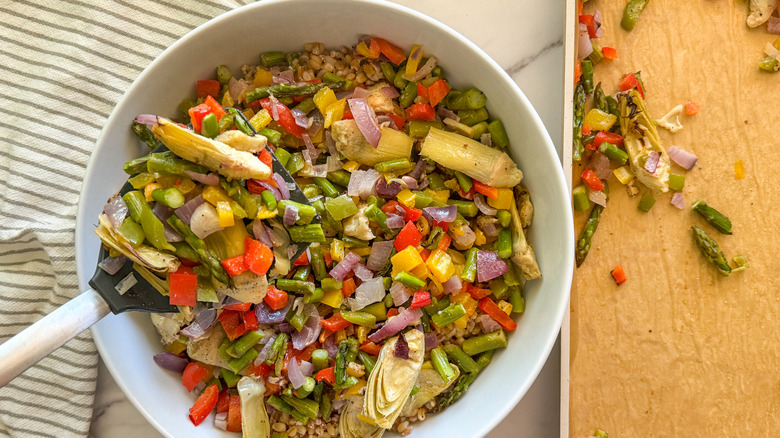 adding roasted vegetables to salad