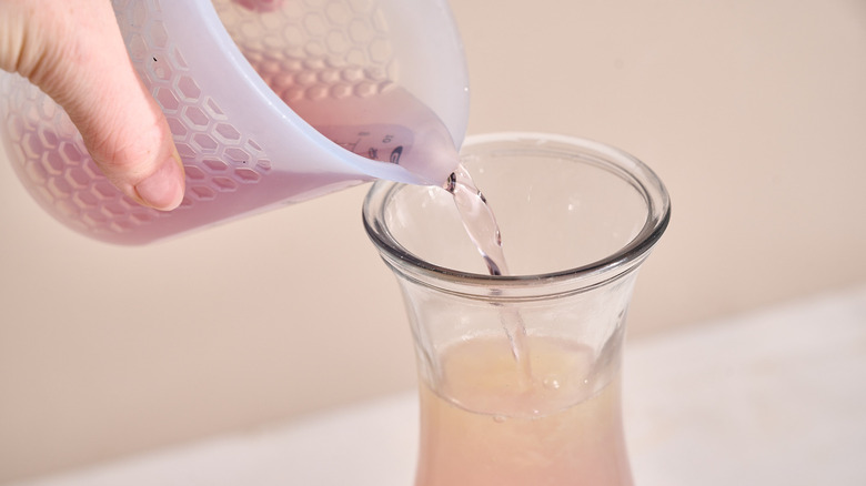 pouring lavender syrup into lemonade