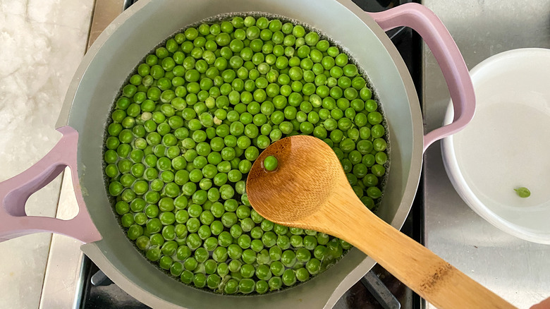 stirring peas with wooden spoon