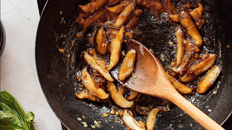 stirring mushrooms in wok