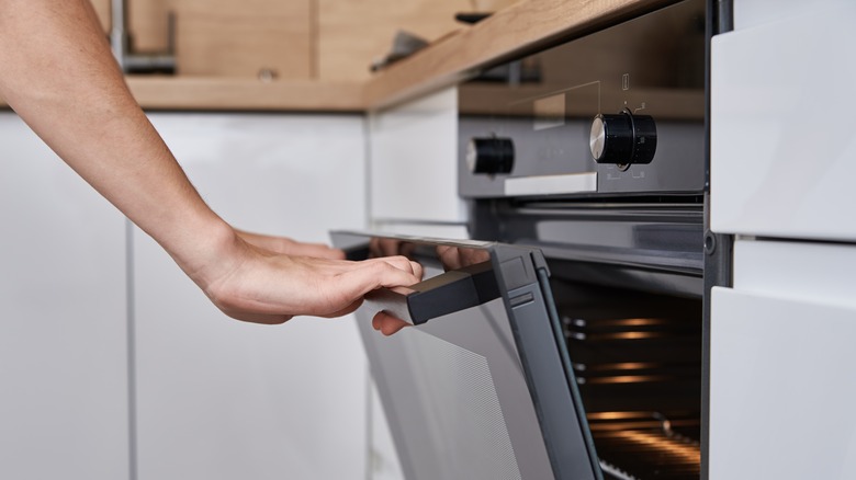 A hand opening an oven