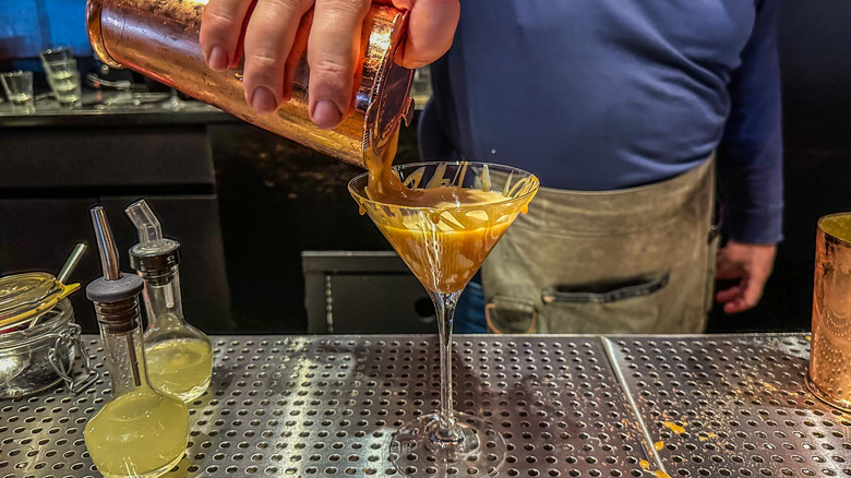 bartender pouring a martini in a glass