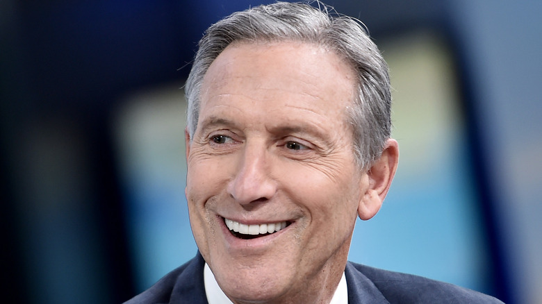 Howard Schultz smiles in suit and white shirt