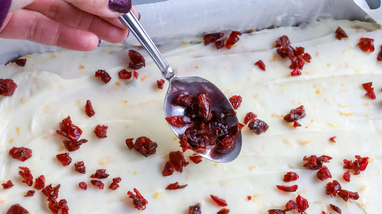 cranberries being spooned onto frosting