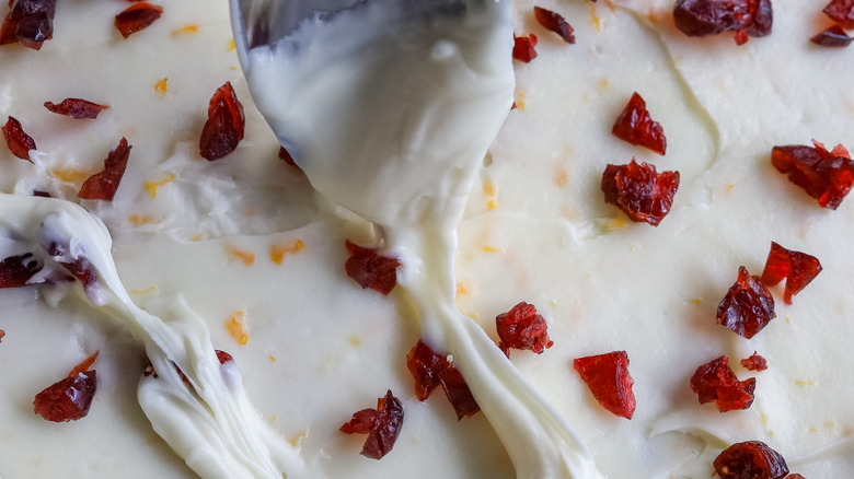 white chocolate being drizzled over cranberry bliss cheesecake bars