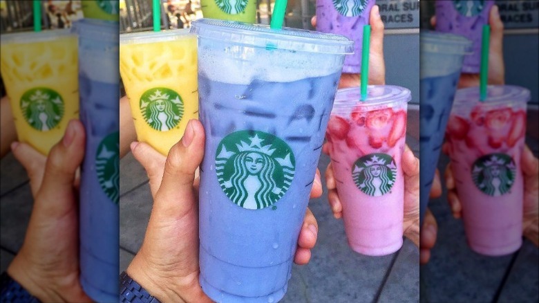 people holding bright starbucks drinks