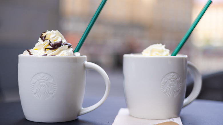 Mugs of Starbucks coffee with whipped cream and straws