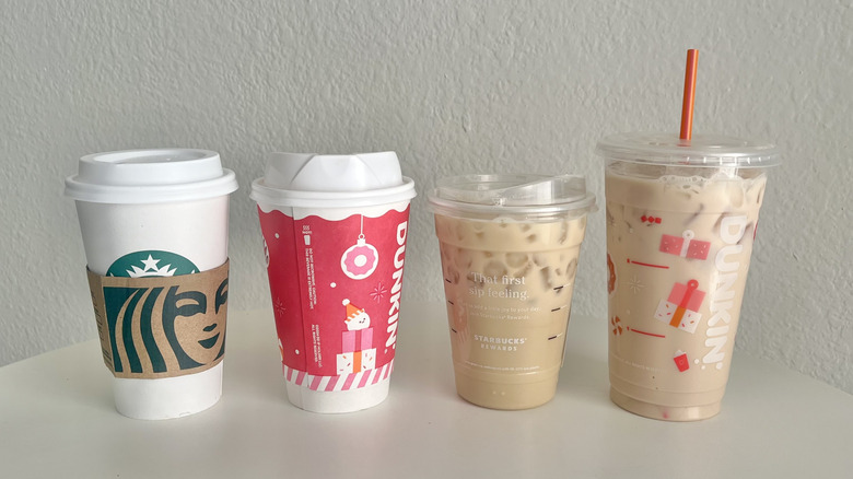 Four chai lattes from Starbucks and Dunkin' are lined up on a white table.