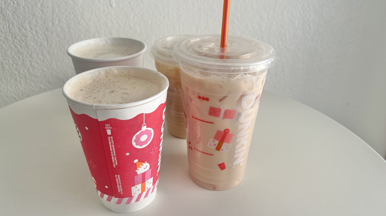 Four chai lattes from Starbucks and Dunkin' are arranged on a table.