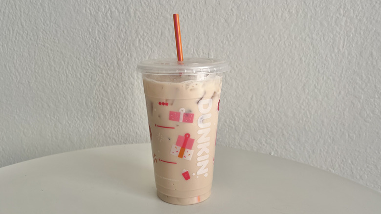 A Dunkin iced chai latte is in a cup with a red straw.