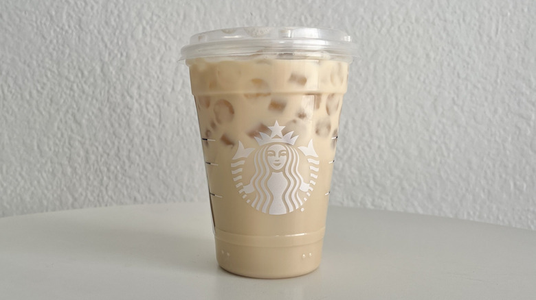 A Starbucks iced chai latte is in a clear cup on a white table.