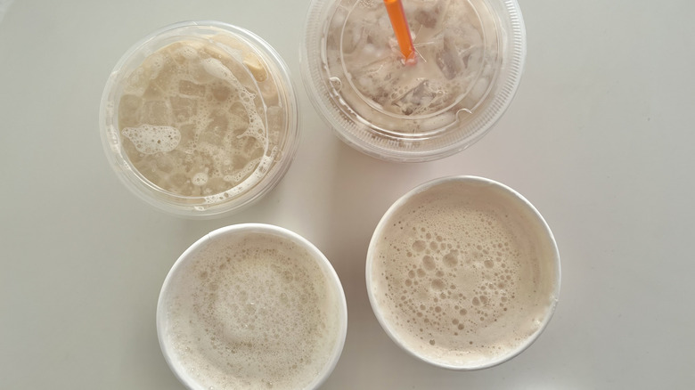 Four chai latte drinks from Starbucks and Dunkin' are viewed from above.