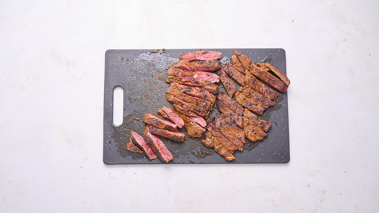 slicing steak on cutting board