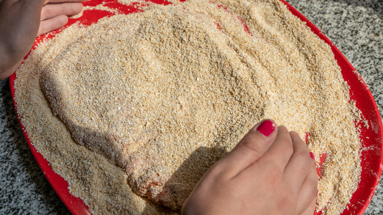 person preparing steak milanesa