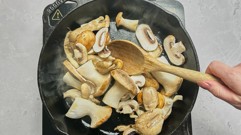 stirring mushrooms in skillet