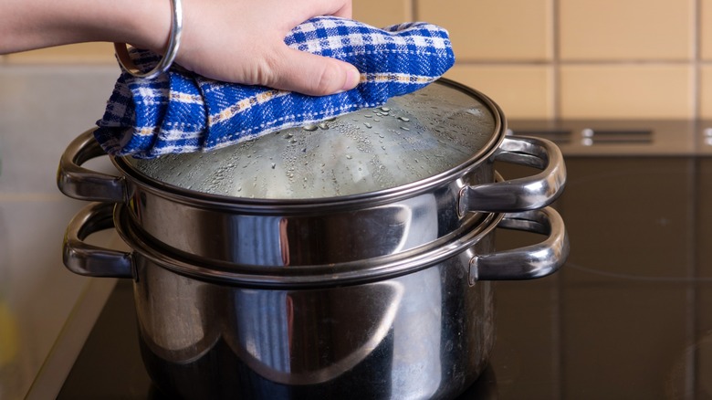 Hand putting a lid on a cooking steam basket