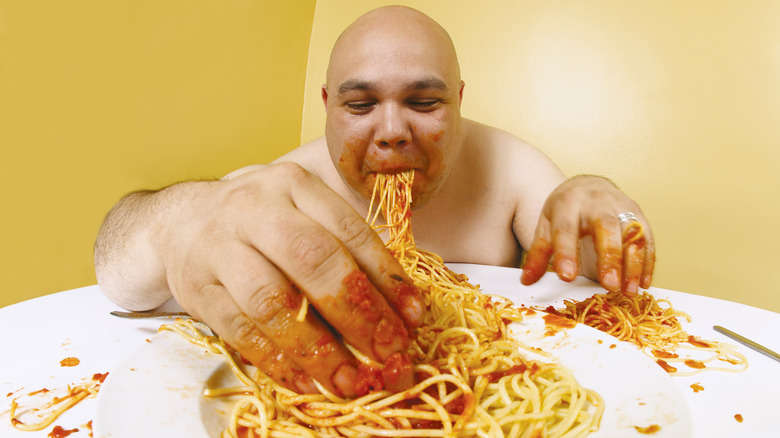 naked man sloppily eating spaghetti 