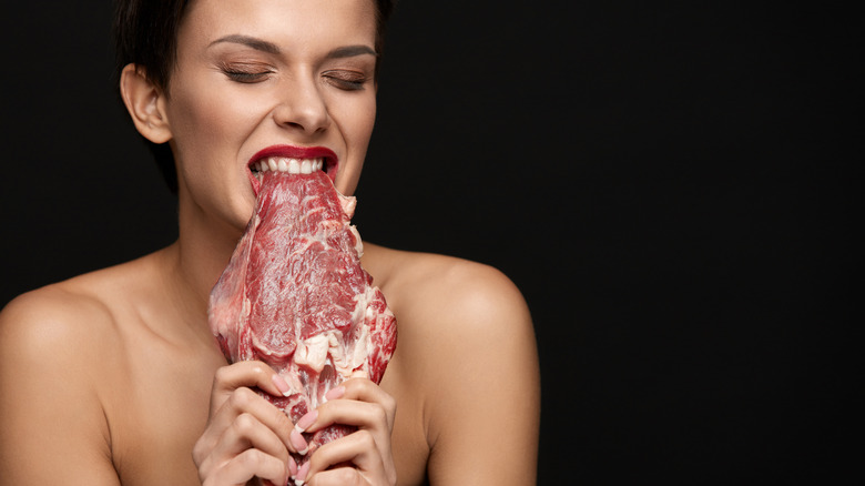 women biting raw steak