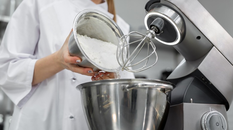 Chef adds flour to bowl 