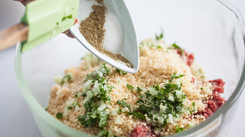 Mixing ground beef with riced cauliflower, herbs, and onions