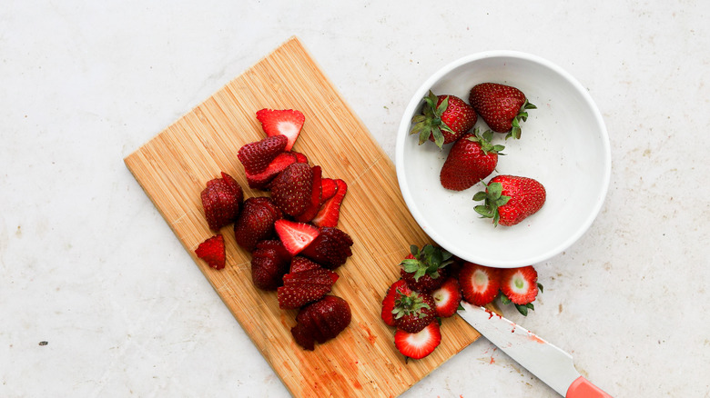 Cutting ripe strawberries on board