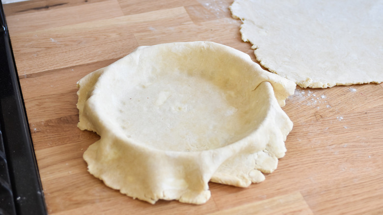 adding pie dough to pan