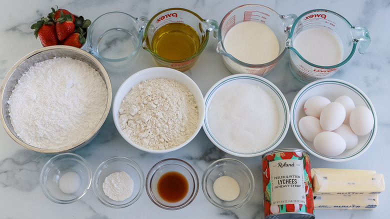 Strawberry, coconut, and lychee layer cake ingredients on a table