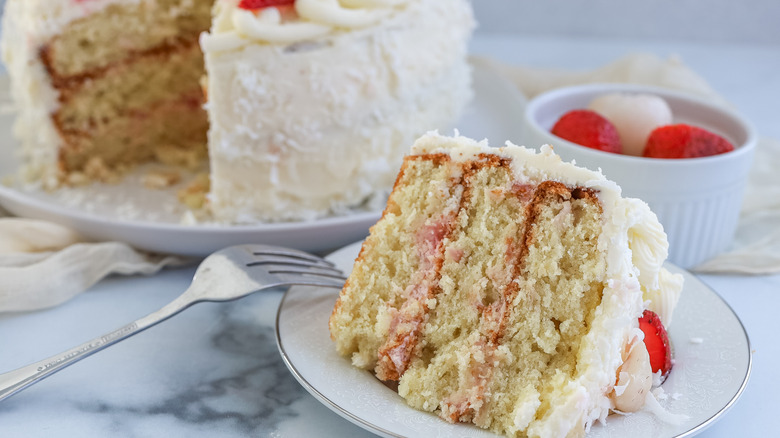 Close up of a slice of strawberry, coconut, and lychee layer cake on a table