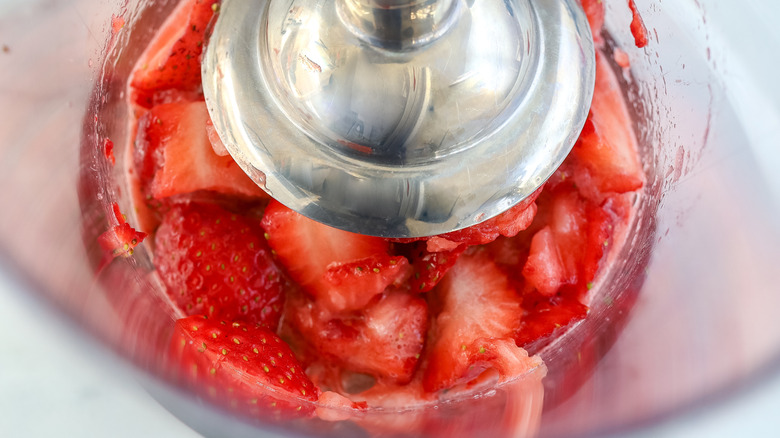 Strawberries being pureed with an immersion blender