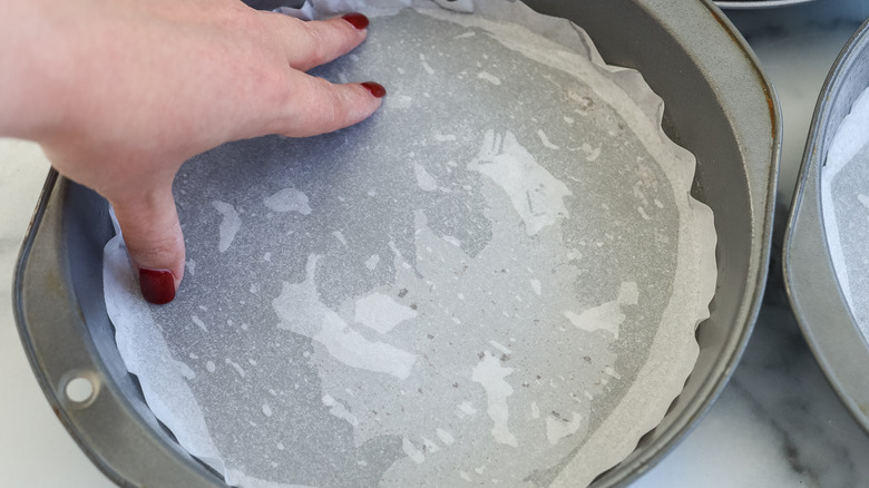 Cake pans being lined with parchment paper