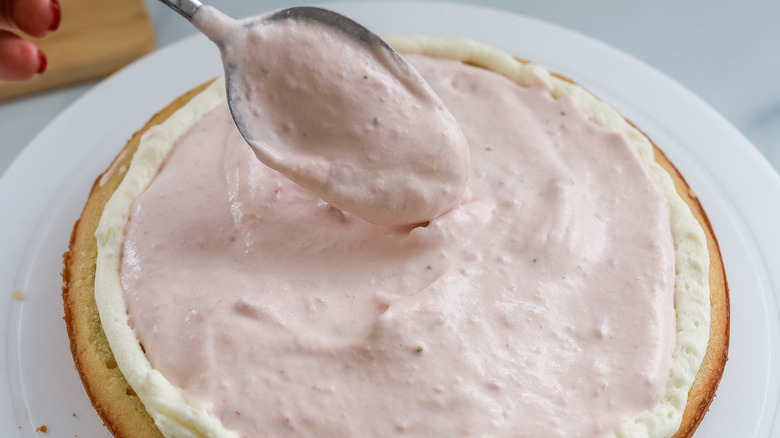 Strawberry Bavarian cream being spooned onto a cake