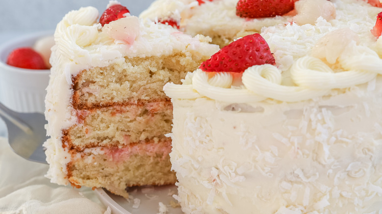 Strawberry, coconut, and lychee layer cake being sliced