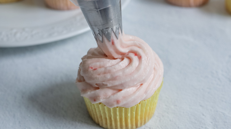 frosting a lemon cupcake