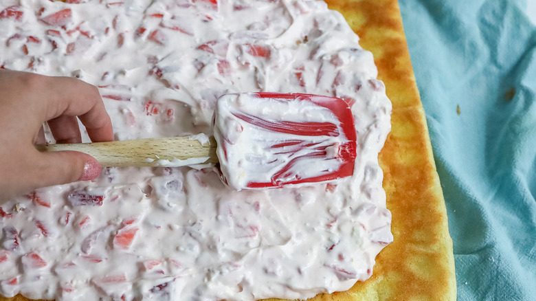 hand spreading frosting on cake