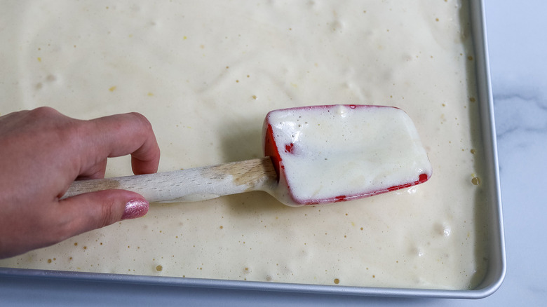 hand spreading batter in pan