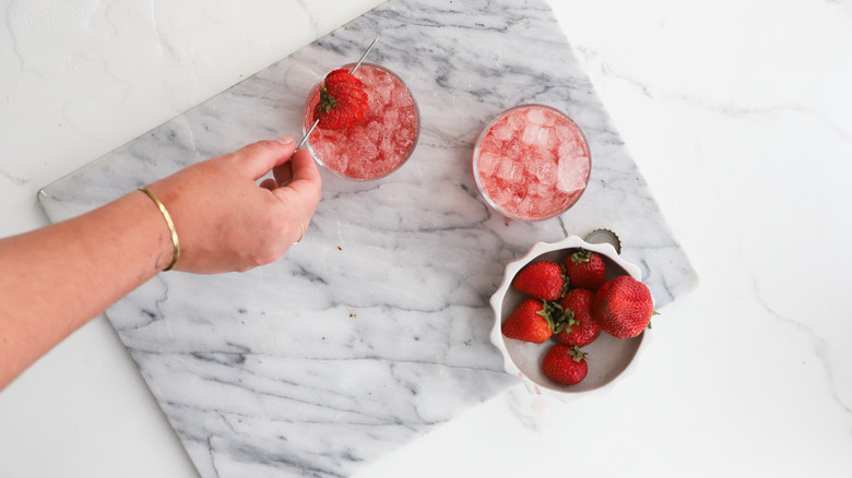 Garnishing two cocktails with strawberries