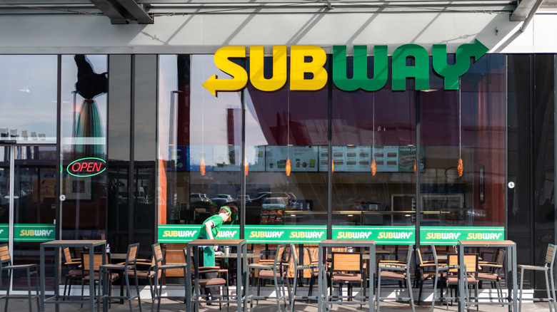 employee cleaning outside subway store