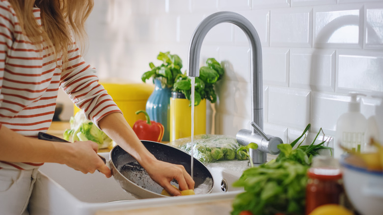 Woman washing pan in sink