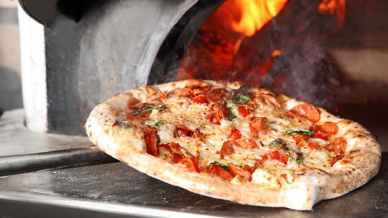 Steaming hot pizza pulled from wood fired oven