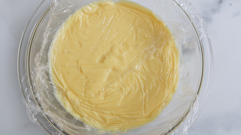 pastry cream in a bowl with plastic wrap over it