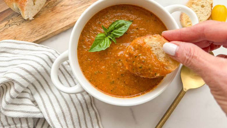 hand dipping bread in soup