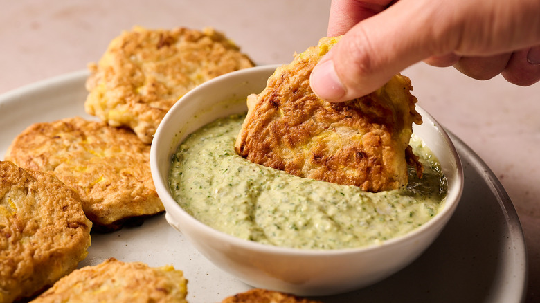 dipping fritter into pesto goat cheese