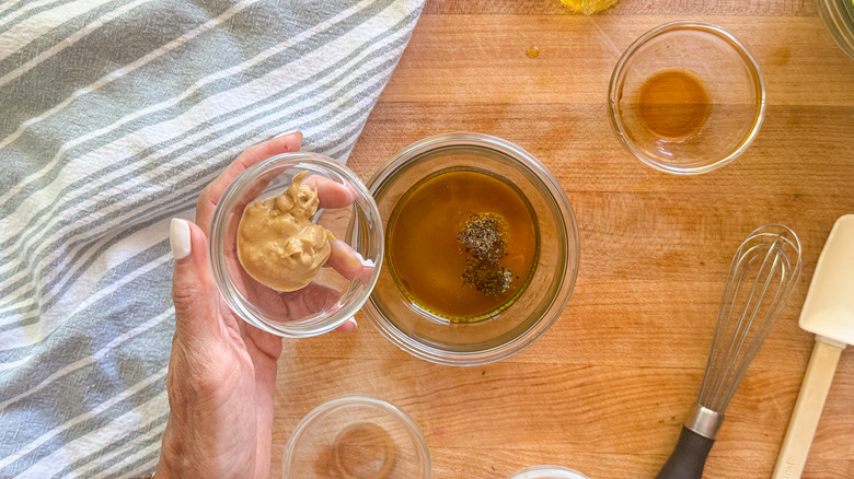 hand adding mustard to bowl