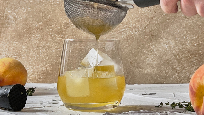 straining cocktail into glass