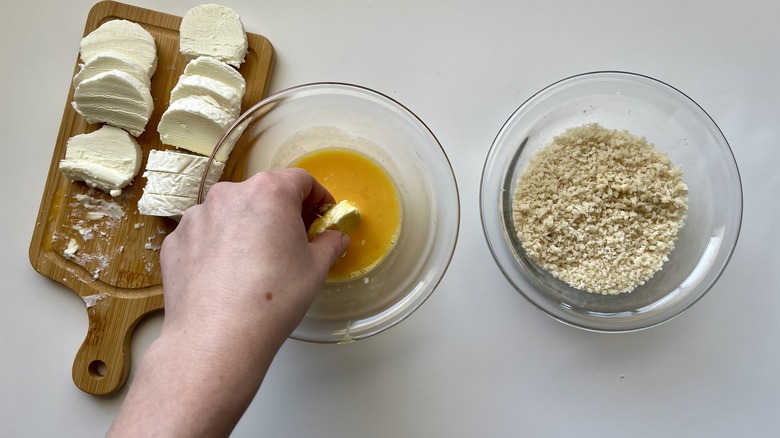 hand dipping cheese in egg