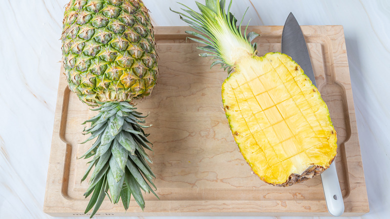 cutting into a pineapple
