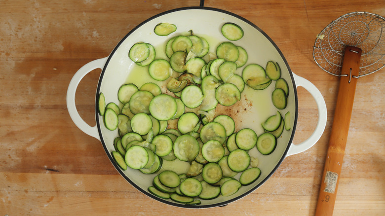 sauteeing zucchini slices in pot