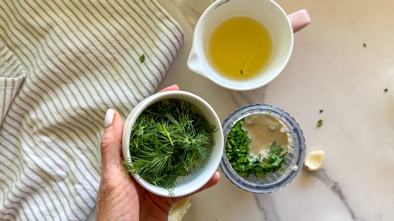 hand adding dill to blender