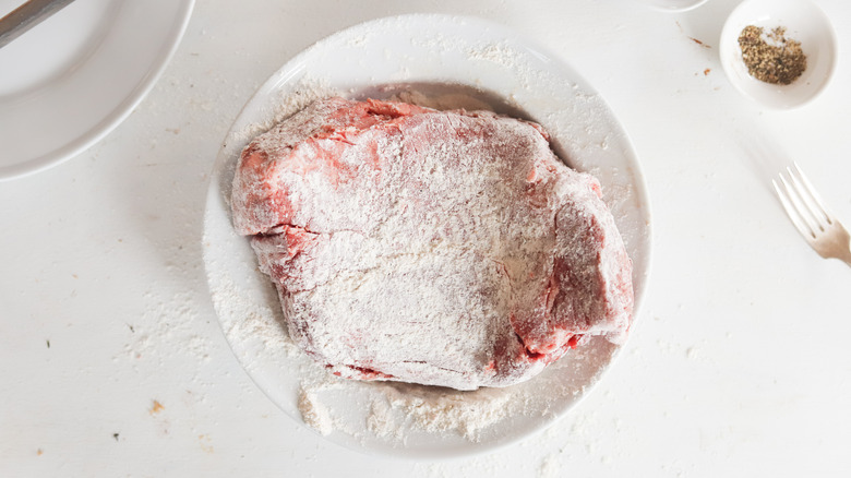 chuck roast coated in flour in white bowl